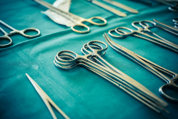surgical instruments and tools including scalpels forceps and tweezers arranged on a table for a surgery